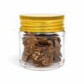 Dried Tuber borchii spring truffle slices in a clear glass jar with a gold lid