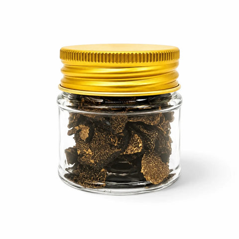 Dried Tuber brumale black winter truffle slices in a clear glass jar with a yellow lid
