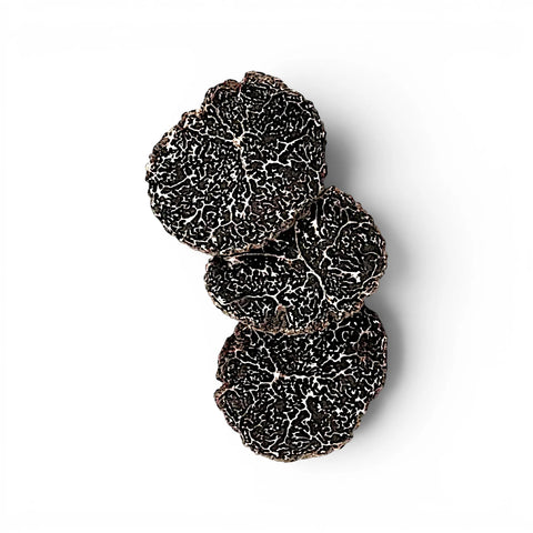 Fresh Tuber melanosporum slices showing dark marbled interiors and natural shape variation