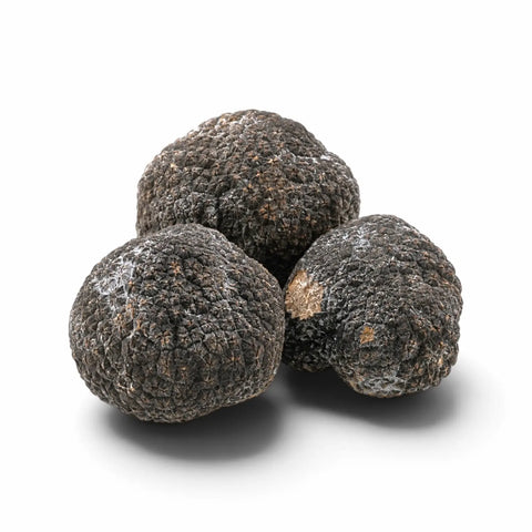 Three whole frozen truffles with light natural frost on a white background