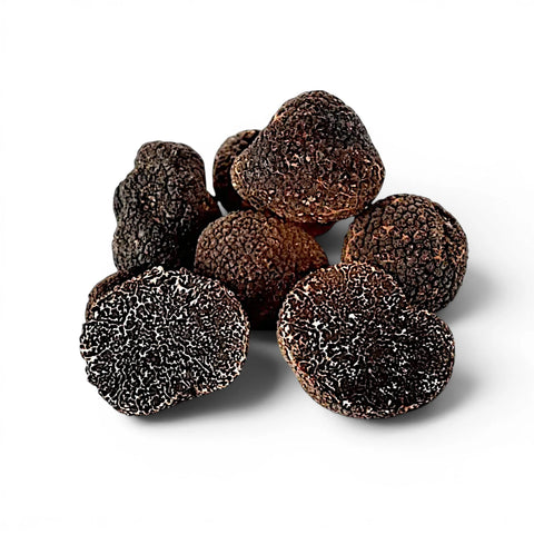 Fresh Tuber melanosporum EXTRA Grade truffles with one cut specimen showing dark marbled interior